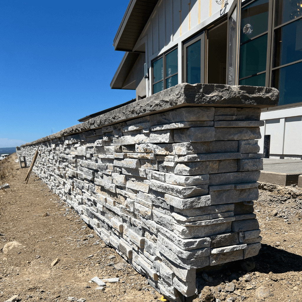 Thin stone veneer installation on custom masonry wall with stone cap